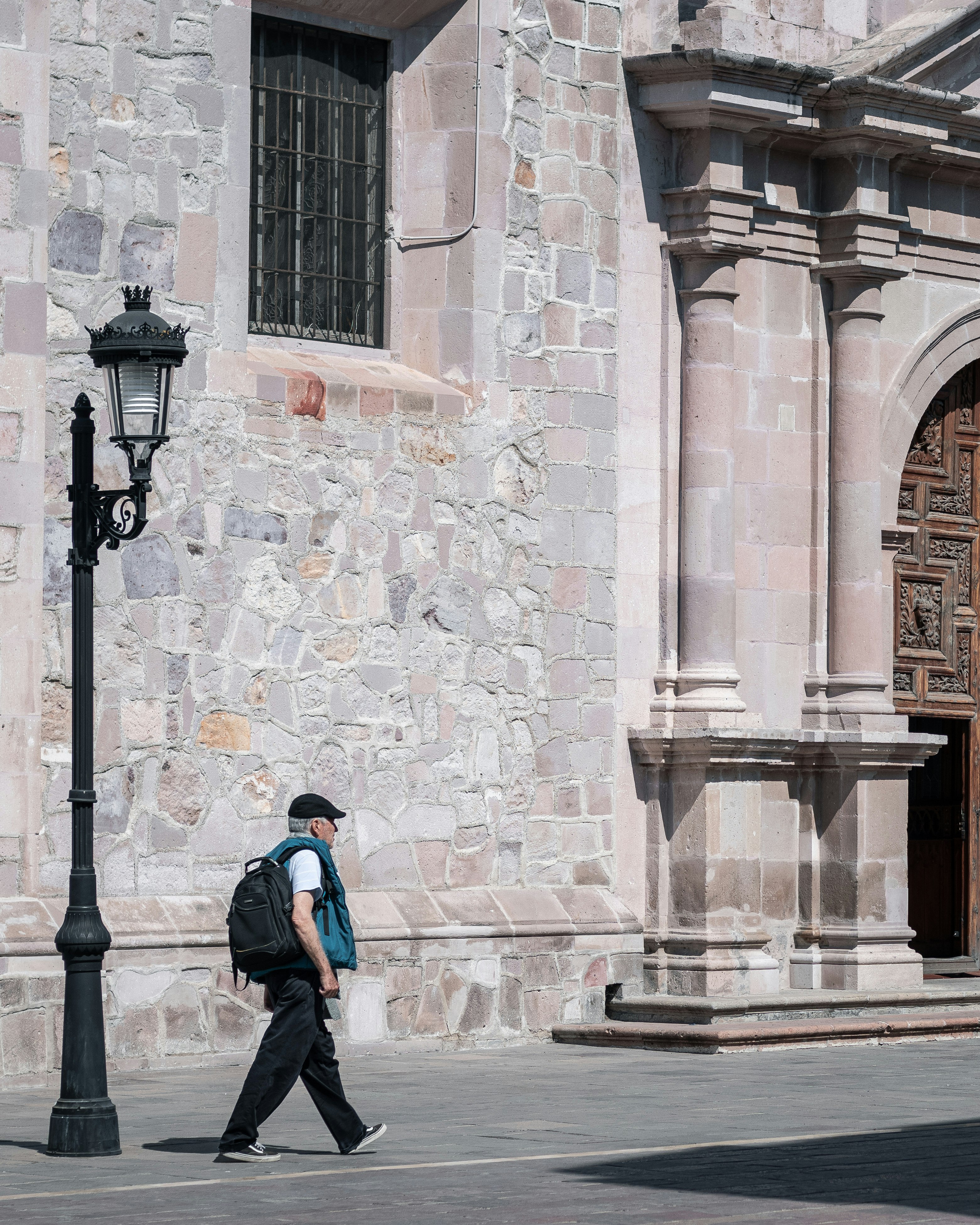 man in blue jacket walking on sidewalk during daytime